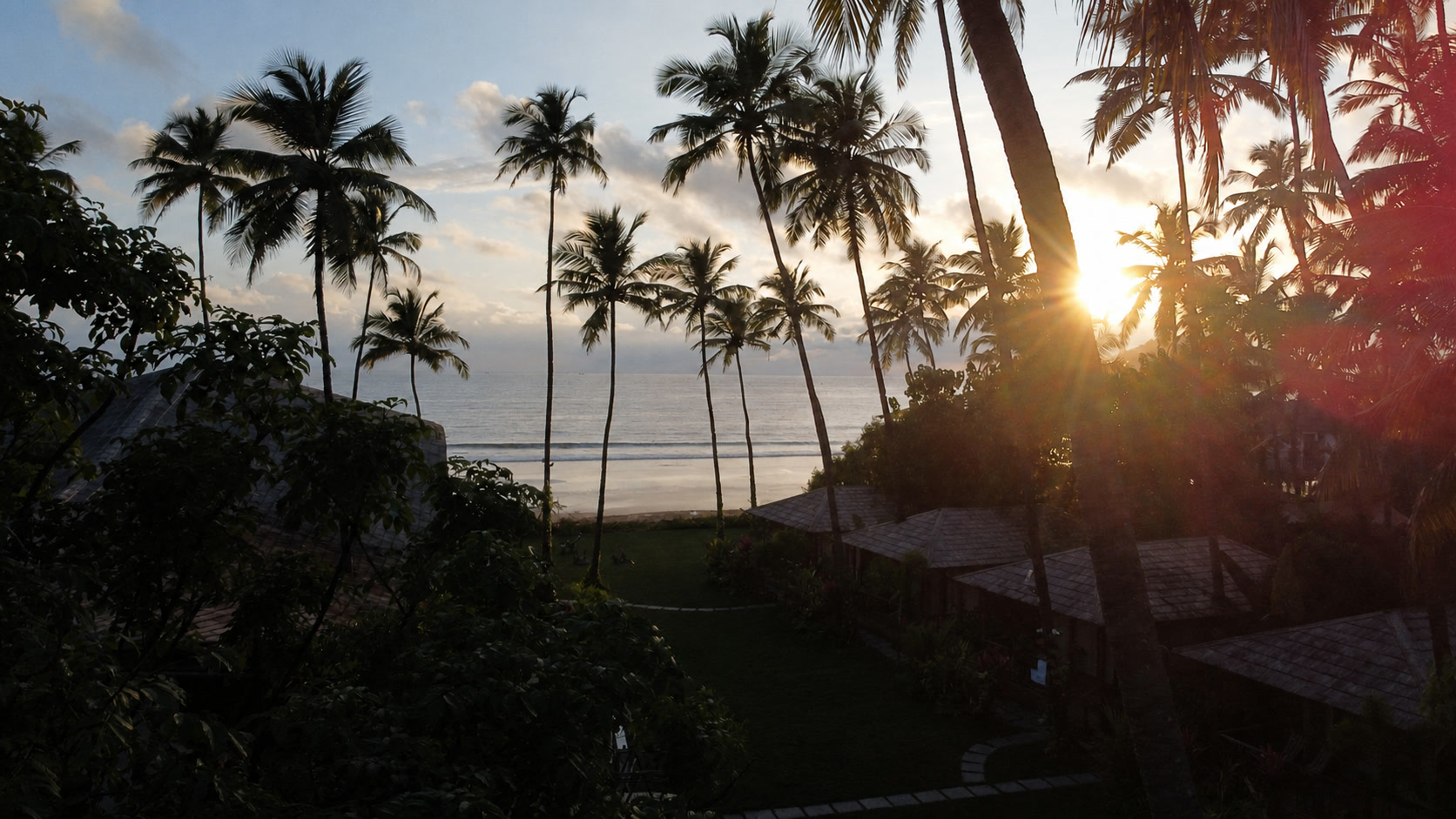 Sunset over Palolem beach through The Wave Goa coconut palms