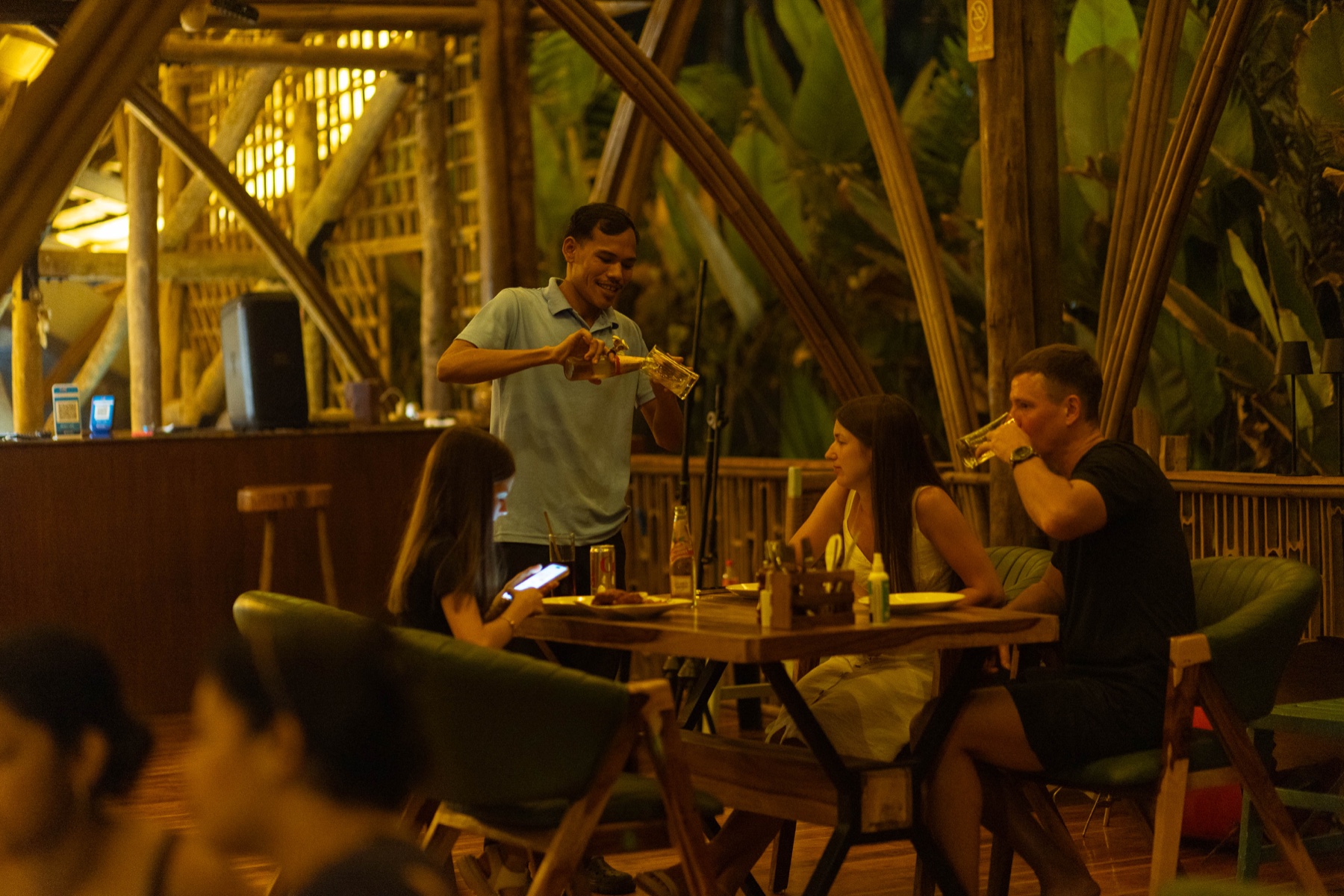 A server pouring drinks for guests dining at The Wave Goa