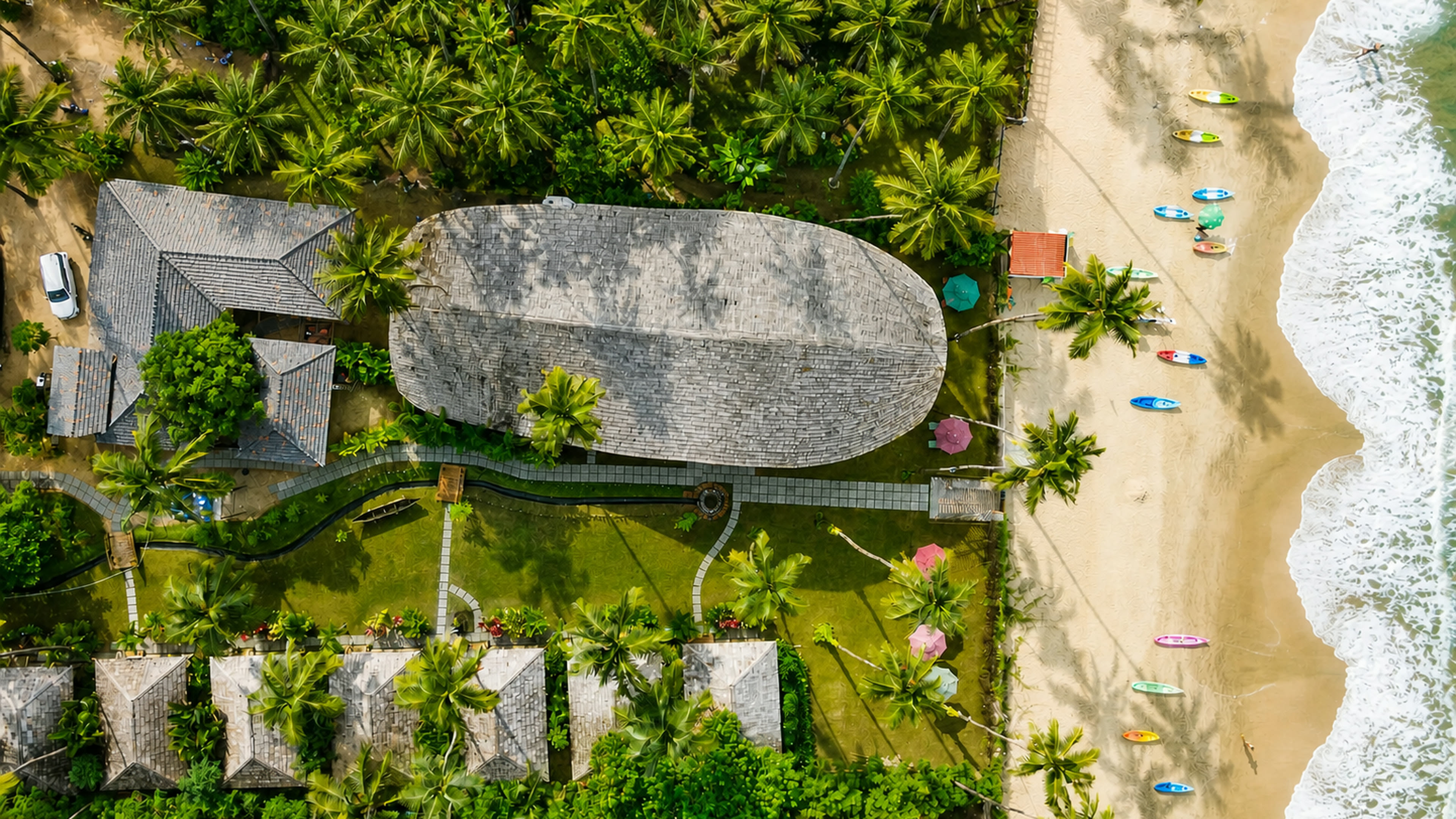Aerial view of The Wave Goa beneath coconut palms beside Palolem Beach